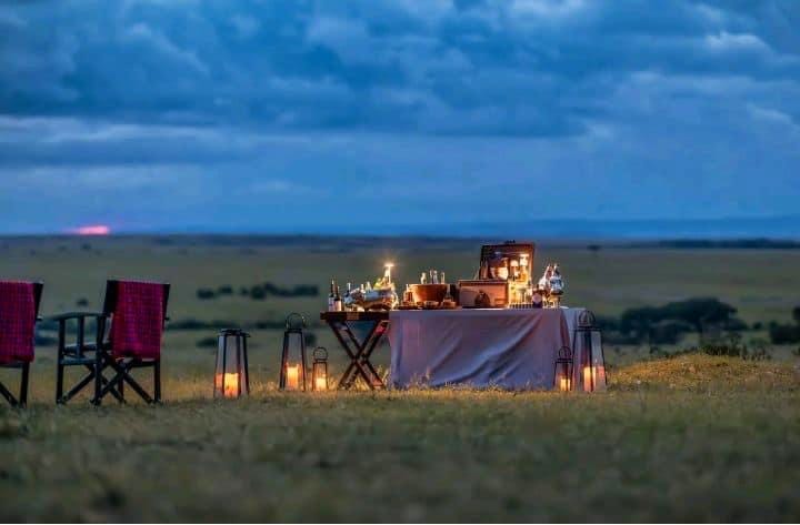 A bush dinner laid out on the plains at dusk